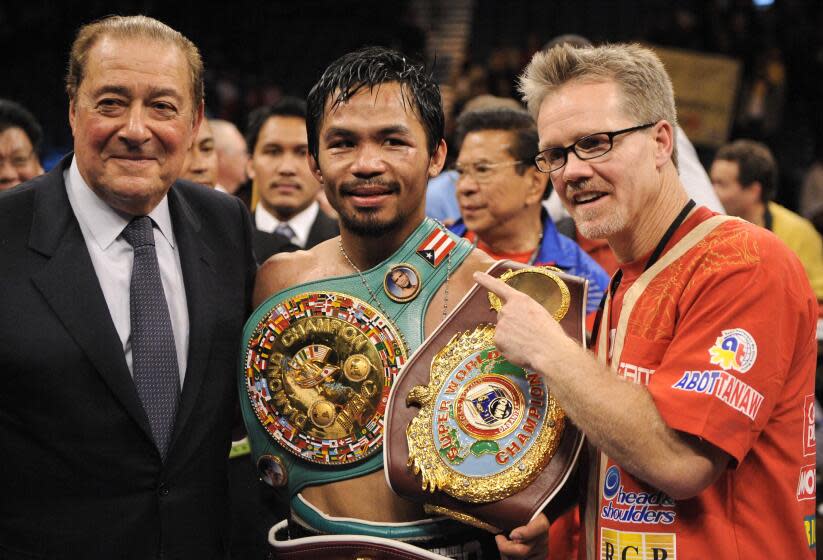 Manny Pacquiao stands between promoter Bob Arum, left, and trainer Freddie Roach after winning a WBO welterweight title fight against