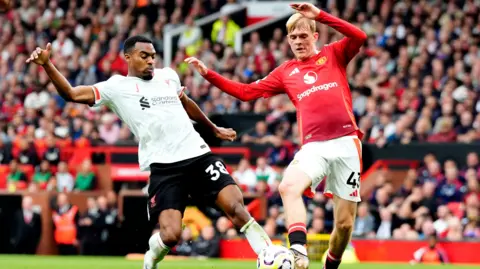 PA Media Liverpool's Ryan Gravenberch battles for possession of the ball with Manchester United's Toby Collyer, (right) during the Premier League match at Old Trafford, Manchester.