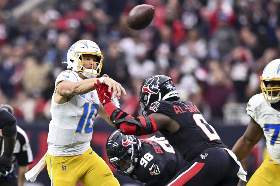 Chargers quarterback Justin Herbert (10) throws under pressure from the Texans' defense in their playoff game.