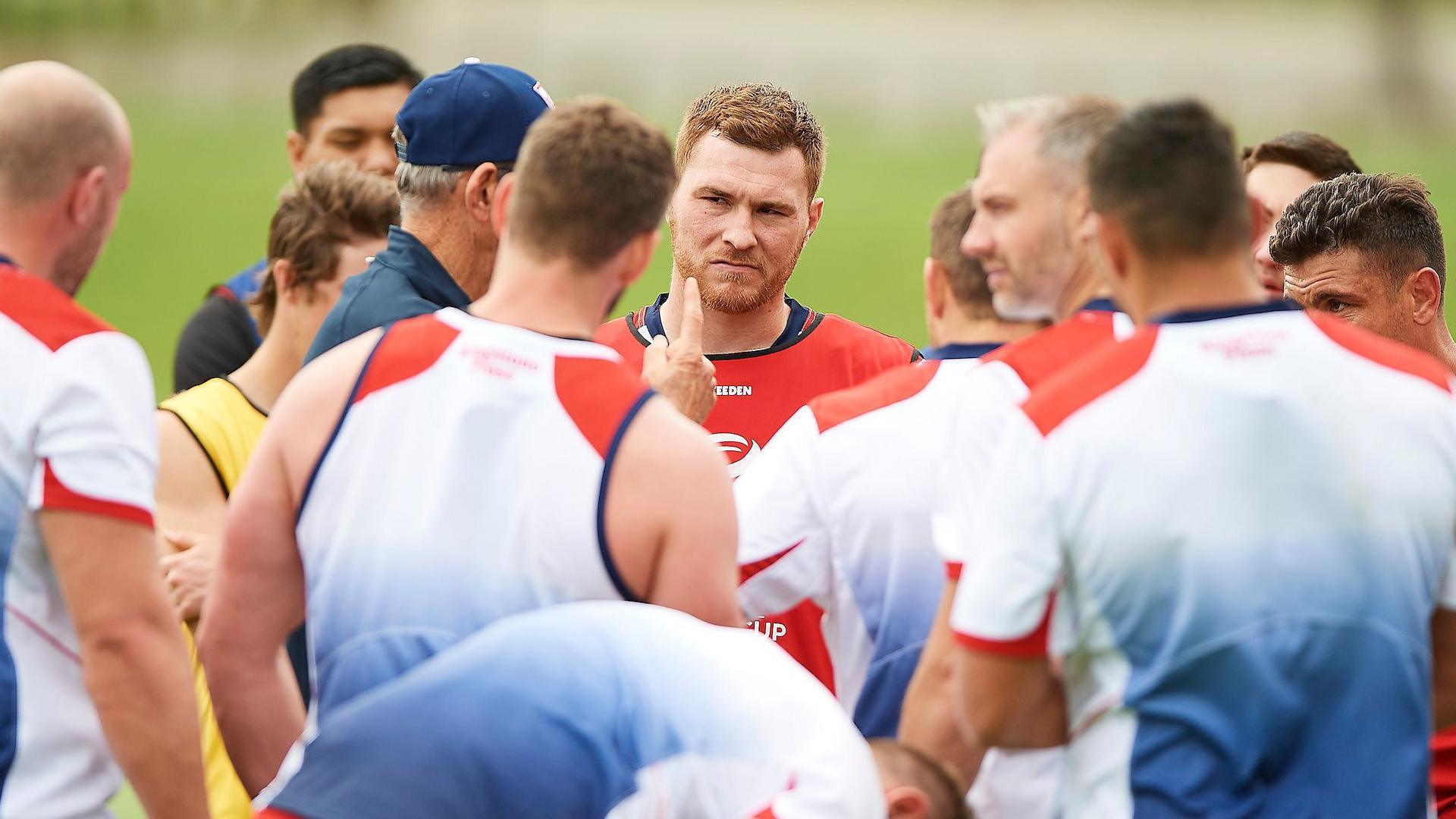 England players including Scott Taylor stand in circle as coach Wayne Bennett delivers his thoughts