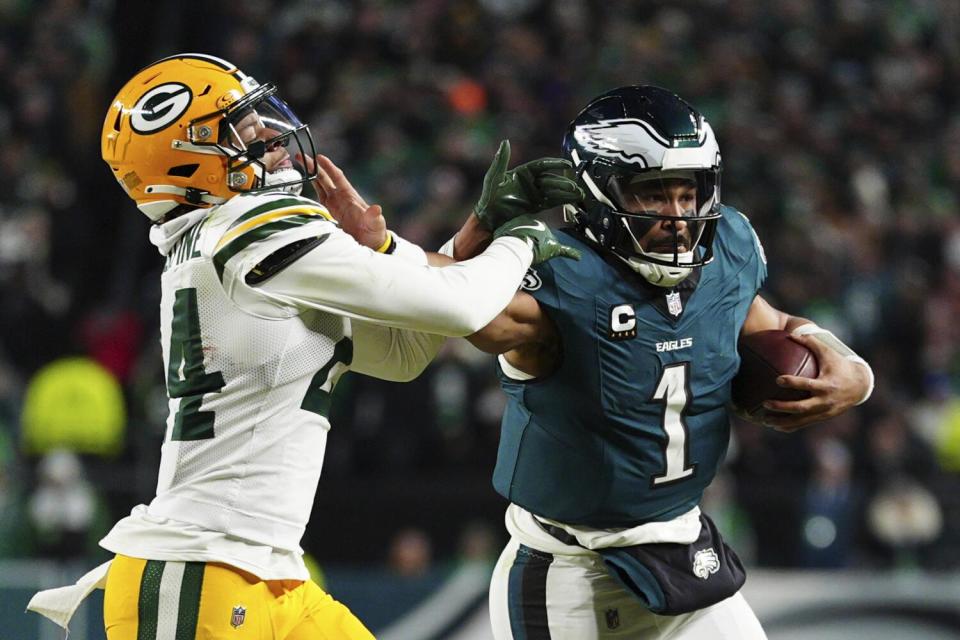 Philadelphia Eagles quarterback Jalen Hurts stiff arms a Green Bay Packers cornerback Carrington Valentine.