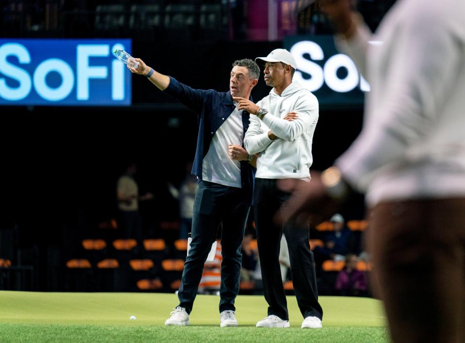 Rory McIlroy and Tiger Woods look over the course as golfers warm up for the inaugural golf match at SoFi Center, the home of TGL, the interactive golf league founded by Tiger Woods and Rory McIlroy on January 7, 2025 in Palm Beach Gardens, Florida.