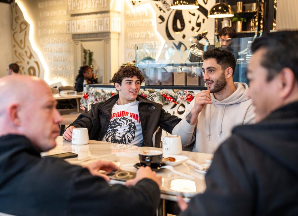 Austin Bashi, left, of West Bloomfield, shares a laugh with fellow fighter Karlo Bashi, right, as they sit with Warrior Way Martial Arts Allnc head instructor Brandon McDaniel, foreground left, and coach Matee Tongbua, foreground right, of West Bloomfield, while getting coffee at Matari Coffee Co. in West Bloomfield on Friday, December 20, 2024, after MMA and grappling training. Austin Bashi is about to make his UFC debut in early January in Las Vegas and is regarded as the top UFC prospect in the country.