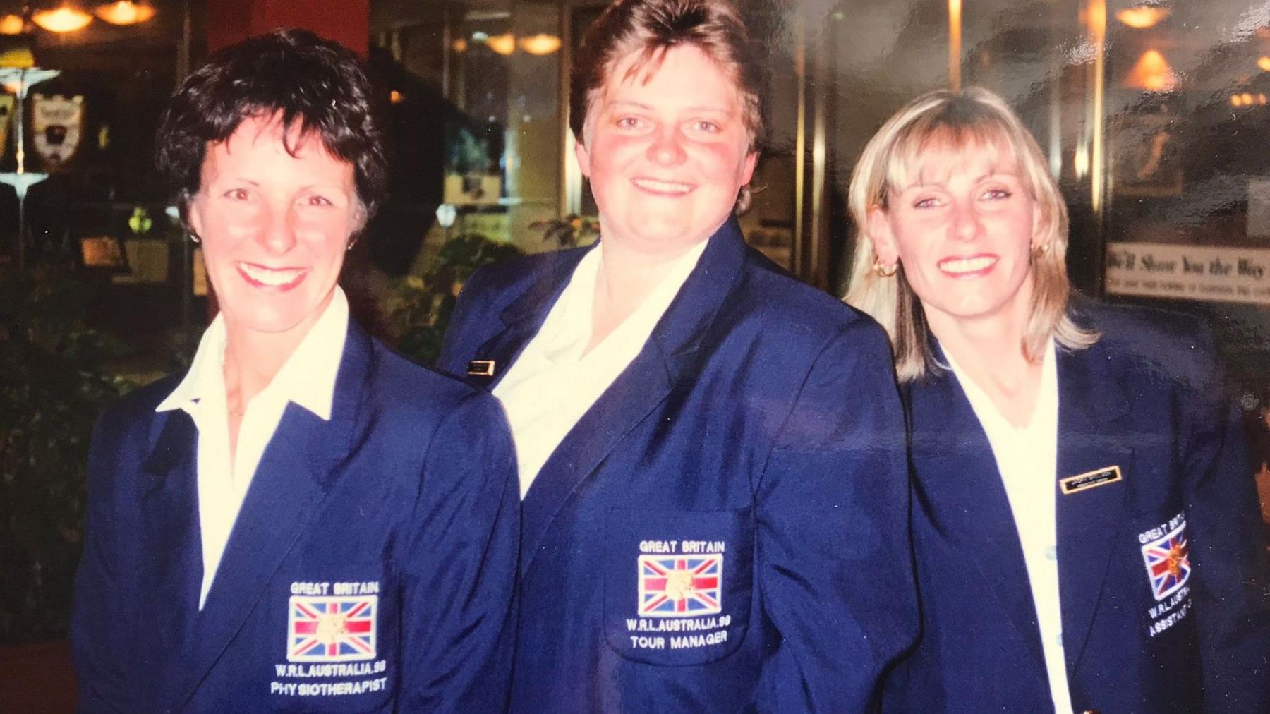 Paula Clark, Nikki Carter and Jackie Sheldon, wearing their team suits, smile for a photograph