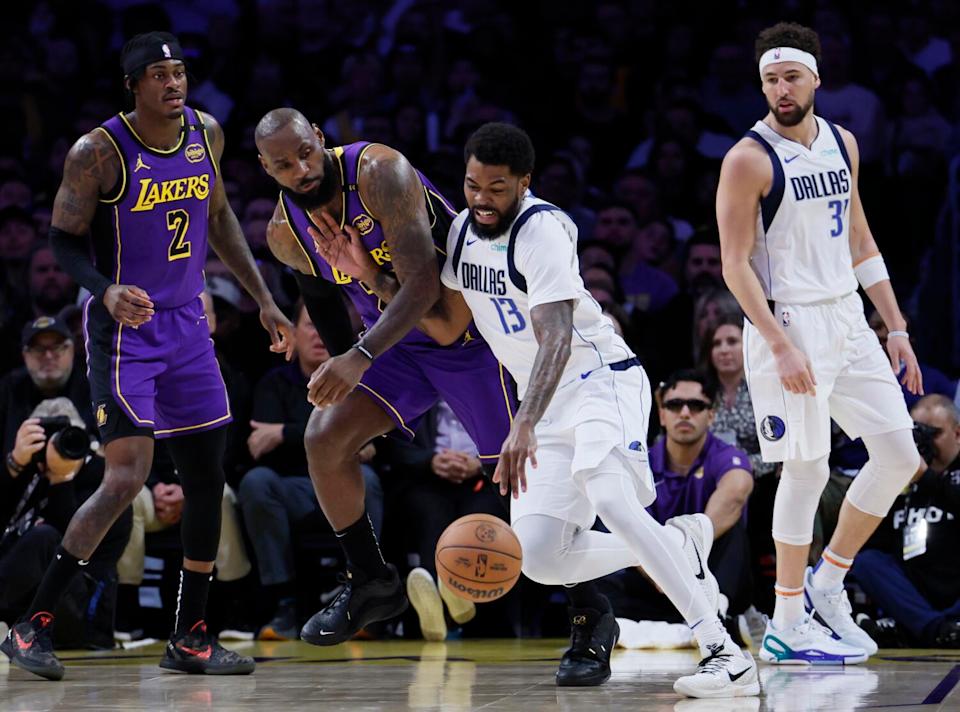 Lakers forward LeBron James, center left, guards Mavericks forward Naji Marshall at Crypto.com Arena on Tuesday.