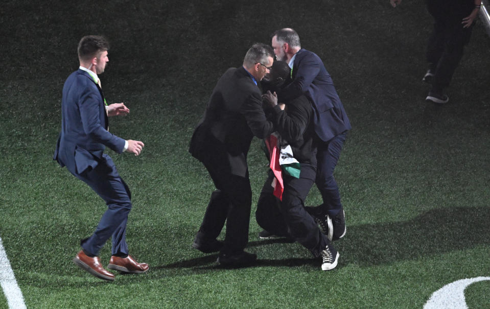 Security grabs a protestor holding a Palestinian flag with the words