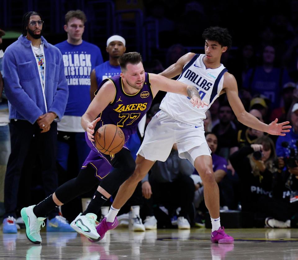 Anthony Davis watches from the sideline as Luka Doncic drives the hoop past Max Christie