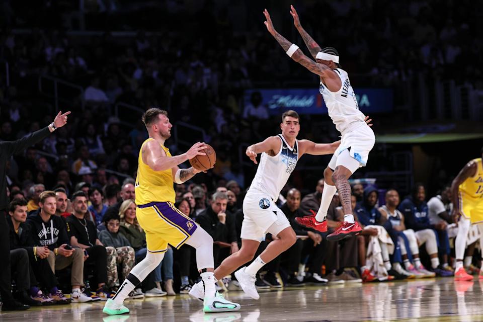 Lakers guard Luka Doncic, left, tries to pass around leaping Minnesota guard Nickeil Alexander-Walker.