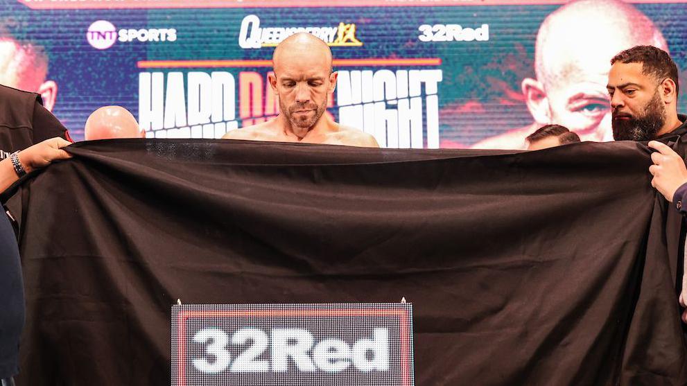 TJ Doheny using a black towel to weigh in