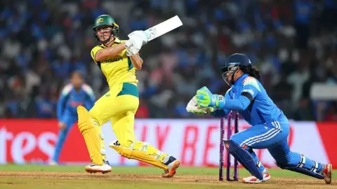 Alex Davidson-ICC/ICC via Getty Images Ash Gardner of Australia bats as wicket keeper Richa Ghosh of India looks on during the ICC Women's Cricket World Cup India 2025 Semi-Final match between India and Australia at DY Patil Stadium on October 30, 2025 in Navi Mumbai, India. (Photo by Alex Davidson-ICC/ICC via Getty Images)