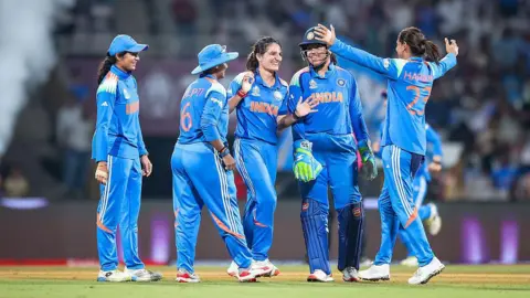 Getty Images Renuka Singh Thakur and other members of India's women cricket team celebrate in the field