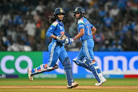 PUNIT PARANJPE/AFP via Getty Images) India's captain Harmanpreet Kaur (R) and Jemimah Rodrigues run between the wickets during the ICC Women's Cricket World Cup 2025 one-day international (ODI) semi-final match between India and Australia at the DY Patil Stadium in Navi Mumbai on October 30, 2025. (Photo by Punit PARANJPE / AFP) / -- IMAGE RESTRICTED TO EDITORIAL USE - STRICTLY NO COMMERCIAL USE -- (Photo by PUNIT PARANJPE/AFP via Getty Images)