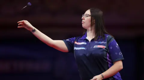 Modus Sports Gemma Hayter wearing purple and throwing a dart on stage.