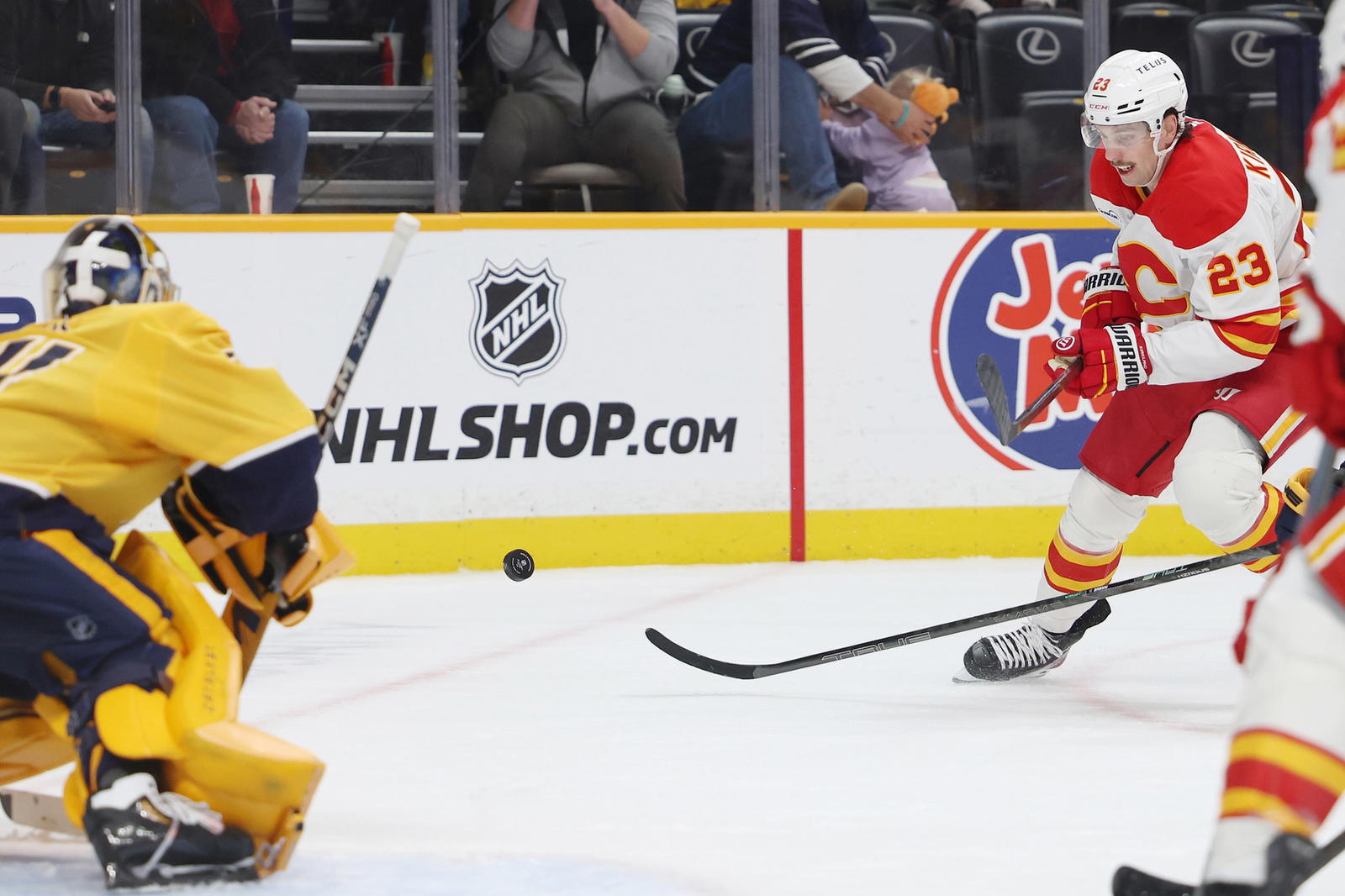 Nov 1, 2025; Nashville, Tennessee, USA; Calgary Flames center Justin Kirkland (23) shoots the puck as Nashville Predators goalie Juuse Saros (74) tends the goal during the second period at Bridgestone Arena. Alan Poizner-Imagn Images